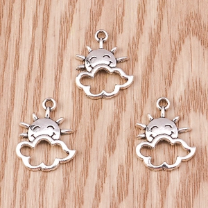 Macro detail of three hollow silver sun and cloud charms on a wooden surface for DIY jewelry
