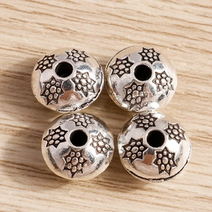 Vista de cuatro cuentas de plata vintage con relieve floral para creación de joyas caseras