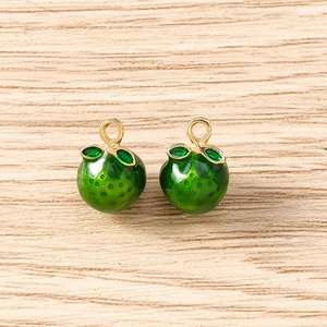 Macro detail of realistic green apple pendants with enamel leaves and gold metal rings