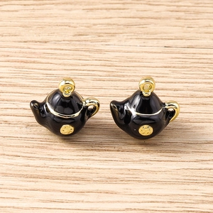 Detailed macro view of black enamel teapot charms with gold-plated alloy finish for DIY jewelry