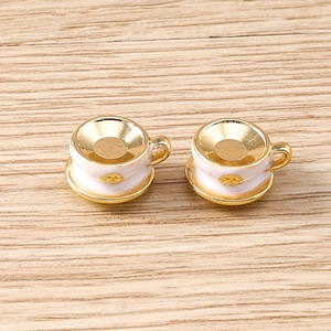 Macro detail of miniature cream and gold coffee cup charms for DIY jewelry making