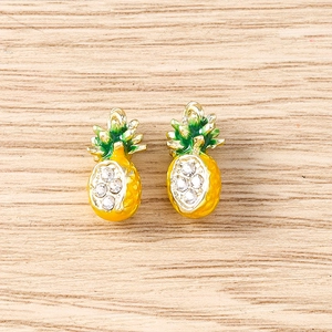 Detail of pineapple pendants with green leaves and inlaid crystals on wood background