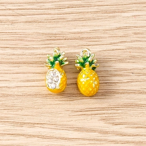 Detailed view of yellow and green pineapple pendants with zircon and enamel finish