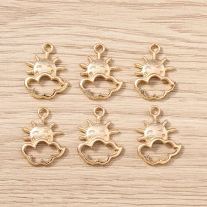 Detailed view of six golden sun and cloud charms arranged on a light wood background