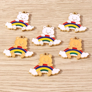 Makro-Detail von sechs Emaille-Bär- und Regenbogen-Anhängern auf hellem Holz
