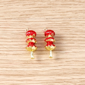 Macro detail of red 3D candied hawthorn charms with gold loop for DIY jewelry making