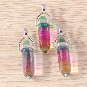 Detail view of hexagonal rainbow crystal bullet pendants on a light wood background
