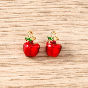Detail of red enamel apple charms with green leaves and gold metal rings for DIY jewelry