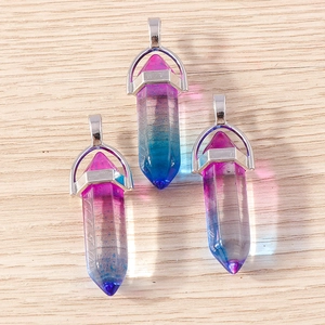 Three gradient purple and blue hexagonal crystal bullet pendants on a wood surface