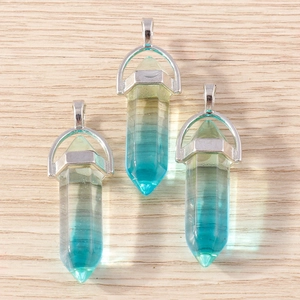 Macro shot of three hexagonal blue and yellow crystal bullet pendants on a wood background