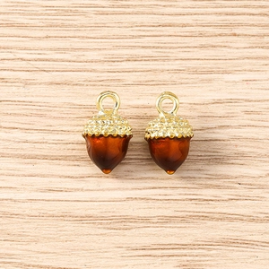 Detail of acorn pendants featuring golden textured caps and amber resin drops for jewelry