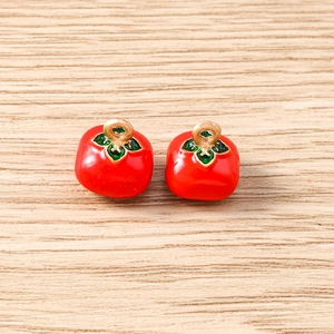 Close-up of 3D red persimmon pendants with enamel finish and golden hanging loops