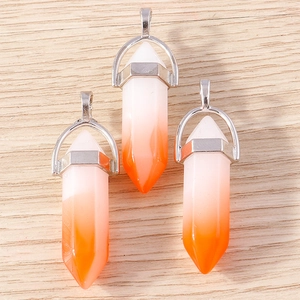 Three orange and white gradient crystal bullet pendants with silver metal clasps on wood