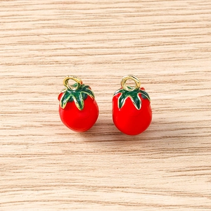 Close-up of red tomato vegetable charms with green leaves and gold metal hanging loops