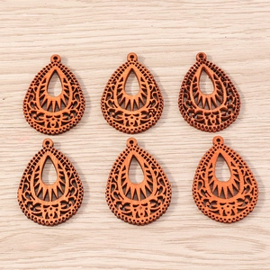 Detailed macro view of six teardrop-shaped dark wood pendants with hollow ethnic patterns