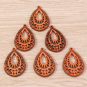 Macro detail of laser-cut teardrop wooden pendants with intricate hollow patterns