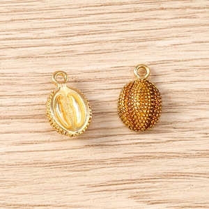 Macro detail of gold 3D fruit vegetable pendants with textured surface for jewelry making