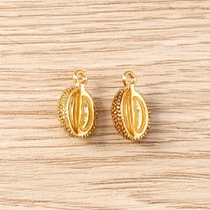 Detail of golden coffee bean charms with realistic texture on a light wood surface