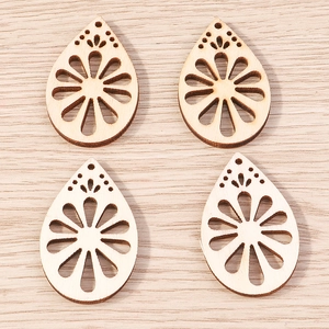 Detailed macro view of four laser-cut wooden teardrop pendants with hollow floral patterns