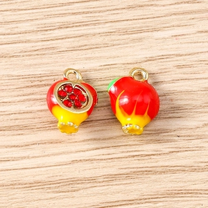 Macro shot of 3D pomegranate charms with enamel finish and red crystal seeds