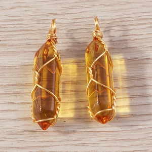 Detail of amber hexagonal bullet pendants with golden wire wrap for jewelry making