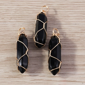Three hexagonal black obsidian crystal pendants with gold wire wrap on wood background