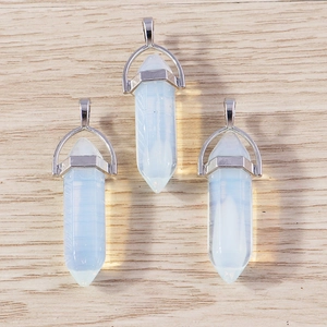 Three hexagonal opalite bullet pendants with silver metal clasps on a wood background