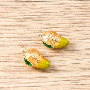 Detailed macro of two orange and green enamel strawberry charms on wooden background