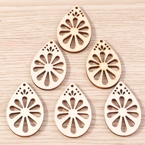 Macro detail of laser-cut wooden teardrop pendants with hollow flower design for DIY