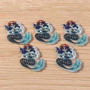 Macro view of five acrylic Day of the Dead mermaid skeleton pendants on a wooden surface