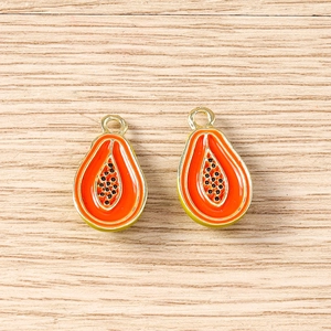 Macro detail of papaya charms with golden edges and orange enamel for DIY jewelry