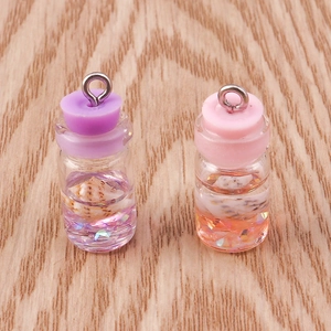 Detailed macro view of mini glass bottle pendants with shells and liquid on wood