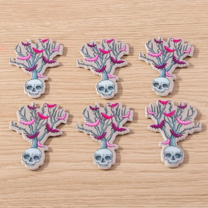 Detailed close-up of acrylic Halloween skeleton bat charms on a light wood background
