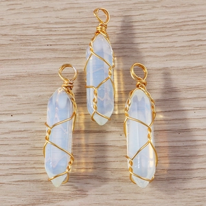 Macro shot of three wire-wrapped opal hexagonal prism bullet pendants on wood