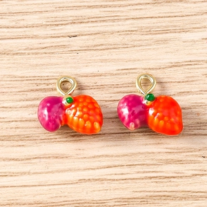 Detail of realistic gradient strawberry charms with gold hooks on a wooden background