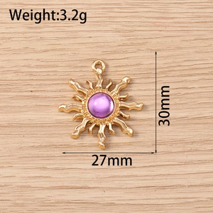 Detail view of 27mm gold sun pendant with purple center stone on wood texture