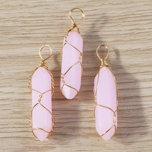 Detailed view of pink hexagonal crystal pendants with gold wire wrapping for jewelry making