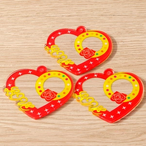 Macro detail of heart-shaped acrylic charms with Love text and rose pattern on wood background