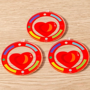 Detailed macro view of three acrylic heart and rainbow DIY pendant charms for jewelry making