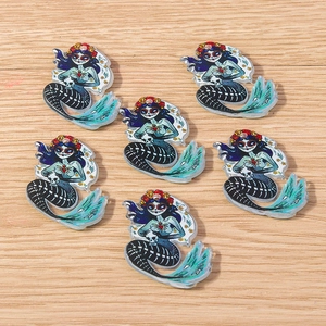 Flat lay of laser-cut acrylic Day of the Dead skeleton mermaid charms for jewelry making
