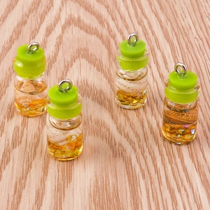 Close-up of glass wishing bottle charms with green stoppers and shells on wood
