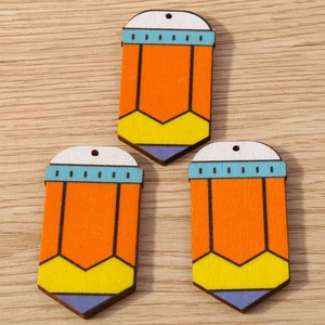 Tres dijes de lápices de madera de colores para joyería DIY en fondo de madera