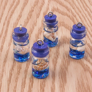 Macro detail of four glass drift bottle pendants with tiny shells and blue sequins inside