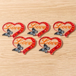 Detail of red acrylic heart pendant with orange Love text and butterfly pattern