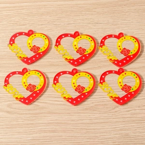 Flat lay detail of six heart-shaped acrylic LOVE pendants on a warm wood background