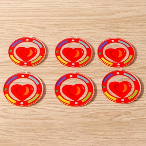 Macro view of round acrylic charms with red heart inlay and rainbow dots for DIY jewelry