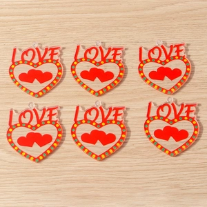 Close-up of heart-shaped LOVE acrylic charms with red and green polka dot details