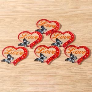 Detail view of 6 red acrylic heart charms with Love text and butterfly design on wood