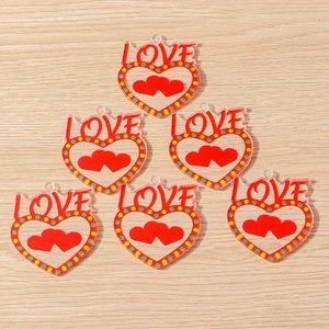 Macro detail of acrylic heart pendants with red LOVE text and polka dots for DIY jewelry