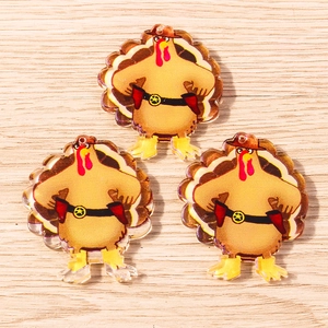 Three acrylic turkey sheriff charms with cowboy hats on a light wood background